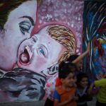 Palestinian children play near murals at Deir al-Balah refugee camp in the central Gaza Strip on May 16