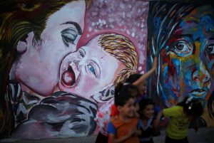 Palestinian children play near murals at Deir al-Balah refugee camp in the central Gaza Strip on May 16