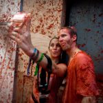 Revellers covered in tomato pulp take a slefie in the annual