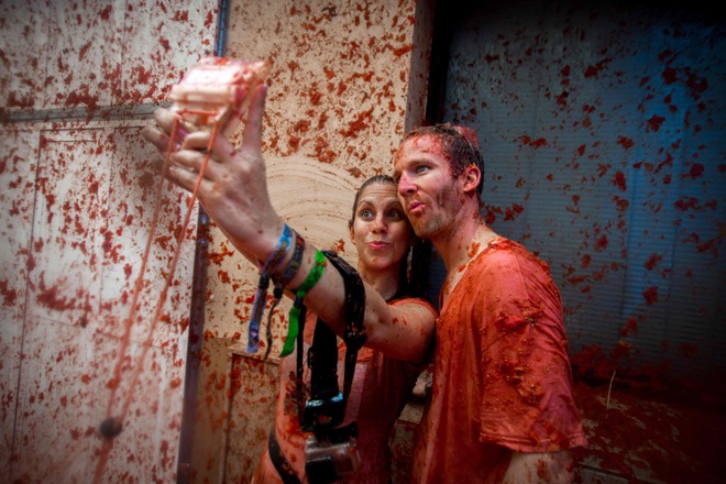 Revellers covered in tomato pulp take a slefie in the annual