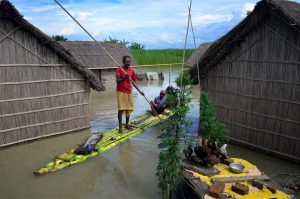 A family using a banana raft at the flood-affected Batahidia in Kamrup, Assam.