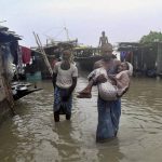 A man carries an aged woman through flood water after their homes submerged in the flood-affected village of Sildobi in Morigaon district in Assam.