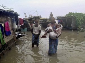 A man carries an aged woman through flood water after their homes submerged in the flood-affected village of Sildobi in Morigaon district in Assam.