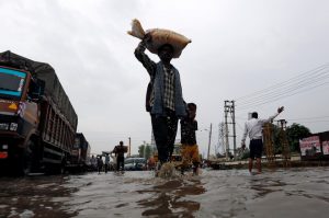 A man carrying his belongings holds hand of his son as they wade through a waterlogged highway in Gurugram, on the outskirts of New Delhi.