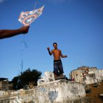 A man (L) helps his friend to fly a kite in a cemetery in the Vila Operaria Favela of Rio de Janeiro, Brazil.