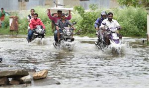Bikers wade through a waterlogged road following rains at the Kodichikkanhalli area in Bengaluru