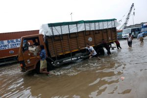 People push a stranded truck in a waterlogged highway after heavy rains in Gurugram, on the outskirts of New Delhi