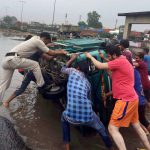 People trying to upright a vehicle overturned due to a pothole on a road in Gurgaon