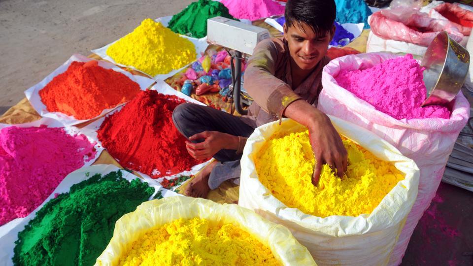 A boy selling colours at a stall waits for customers by a roadside in Gurgaon ahead of Holi