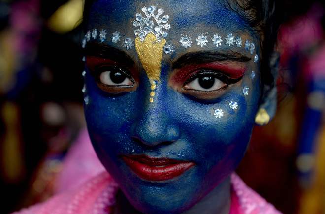 A participant dressed as Lord Krishna looks on during a cultural event in the run up to Janmashtami.