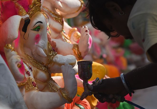 An Indian artisan gives the final touches to a statue of Hindu elephant-headed god, Ganesh at a roadside stall at the start of the Ganesh Chaturthi festival, in New Delhi on September 5, 2016.
