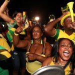 Fans cheer while watching a broadcast of Jamaica's Usain Bolt winning the men's 100 meters final in Kingston, Jamaica.
