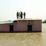 Flood-affected people stand on the roof of a submerged house as they wait to be rescued at Kasimpurchak, near Danapur Diara in Patna in eastern Bihar state