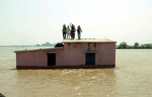 Flood-affected people stand on the roof of a submerged house as they wait to be rescued at Kasimpurchak, near Danapur Diara in Patna in eastern Bihar state
