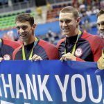 Nathan Adrian, Michael Phelps, Ryan Murphy, and Cody Miller hold a banner during the victory lap after winning gold in the Men’s 4 x 100-meter medley relay final during the swimming competitions at the 2016 Summer Olympics, August 14, 2016, in Rio de Janeiro, Brazil.