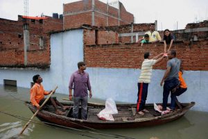 Rescuers distribute food in flooded-effected areas in a residential colony in Uttar Pradesh’s Allahabad on August 23, 2016