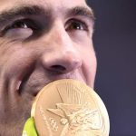 USA’s Michael Phelps kisses his gold medal on the podium after Team USA won the Men’s 4x200m Freestyle Relay Final during the swimming event at the Rio 2016 Olympic Games at the Olympic Aquatics Stadium in Rio de Janeiro on August 9, 2016.