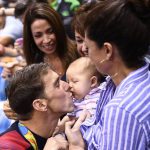 USA’s Michael Phelps (L) kisses his son Boomer next to his partner Nicole Johnson after he won the Men’s 200m Butterfly Final during the swimming event at the Rio 2016 Olympic Games at the Olympic Aquatics Stadium in Rio de Janeiro on August 9, 2016.