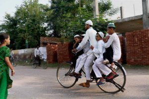 A Muslim boy carries his brothers on a bicycle for offering prayers at a mosque in Patiala on the occasion of Eid al-Adha