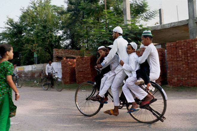 A Muslim boy carries his brothers on a bicycle for offering prayers at a mosque in Patiala on the occasion of Eid al-Adha