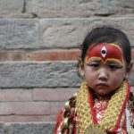 A Nepalese girl dressed as a Kumari, a living goddess, looks on as she takes part in Kumari Puja rituals in Kathmandu.