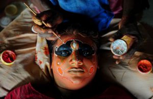 A 'Theyyam' artist gets his face painted before performing during the 'Kummati Kali' as part of the annual Onam festival celebrations in Thrissur district of Kerala state.