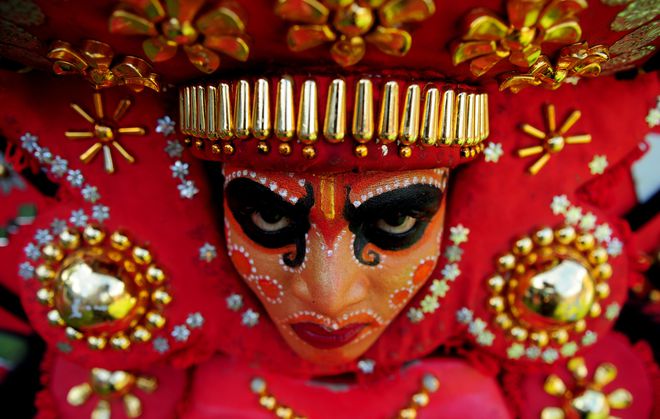 A 'Theyyam' artist with his face painted waits to perform during the 'Kummati Kali' as part of the annual Onam festival celebrations in Thrissur district of Kerala.