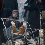 A child pushes a stroller while waiting with others to be evacuated from a rebel-held sector of eastern Aleppo, Syria, on December 16, 2016.