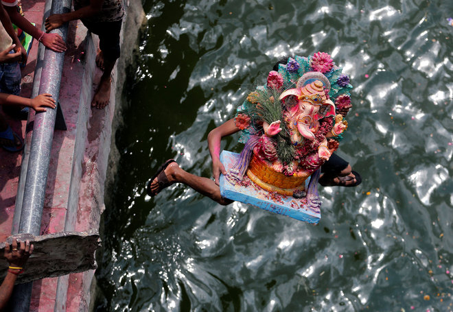 A devotee carrying an idol of the Hindu god Ganesh, the deity of prosperity, jumps into the Sabarmati River to immerse the idol on the last day of the Ganesh Chaturthi festival in Ahmedabad.