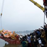 A devotee takes pictures as crane workers immerse a 58-foot idol of the Hindu god Ganesh in the Hussain Sagar Lake during the Ganesh Chaturthi festival in Hyderabad.