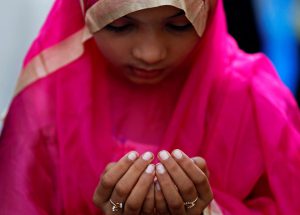 A girl offers Eid al-Adha prayers on a street outside a railway station in Mumbai