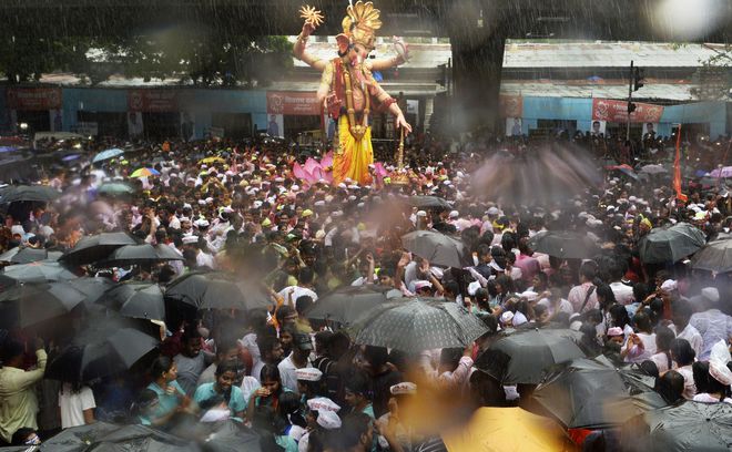 A huge idol of elephant-headed Hindu God Lord Ganesha is seen amidst a sea of devotees during its procession through heavy rain for an immersion in Mumbai.