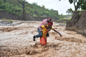 A man is carried across the river La Digue in Petit Goave where the bridge collapsed during the rains of the Hurricane Matthew, southwest of Port-au-Prince, on October 5, 2016.