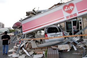 A man stands in front of a damaged vehicle and convenience store after Typhoon Meranti made landfall, in Kaohsiung, Taiwan, on September 15, 2016.