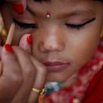 A woman applies makeup to a young girl dressed as the living goddess Kumari during the Kumari Puja festival in Kathmandu.