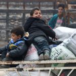 Boys react as they sit on belongings and wait to be evacuated from a rebel-held sector of eastern Aleppo, Syria, on December 16, 2016.