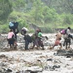 Haitian people cross the river La Digue in Petit Goave where the bridge collapsed during the rains of the Hurricane Matthew, southwest of Port-au-Prince, on October 5, 2016.