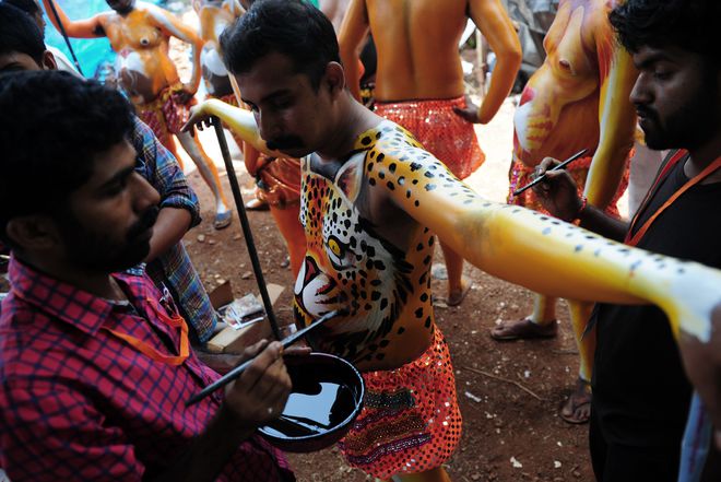 Indian artists paint performers with body-paint depicting tigers as they prepare to take part in the Pulikali, or Tiger Dance, in Thrissur on September 17, 2016. The folk-art event is held every year in the town during the Onam festival.
