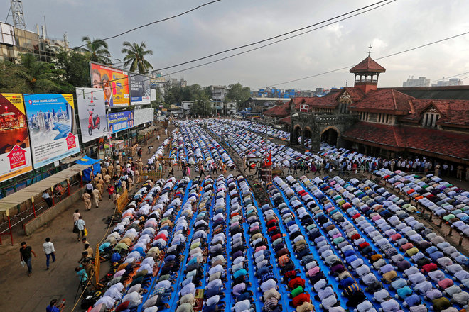 People offer Eid al-Adha prayers on a street outside a railway station in Mumbai