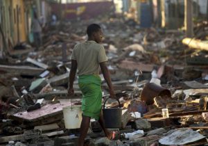 A teenage boy lugs two buckets of water through a street permeated with wreckage caused by Hurricane Matthew in Baracoa, Cuba, on October 7, 2016.