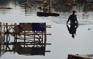 Indian scavengers look for coins and re-usable items amongst the religious offerings and wooden frames of idols of goddess Durga that are piled up in the Yamuna river in New Delhi on October 12, 2016, following the Durga Puja festival.