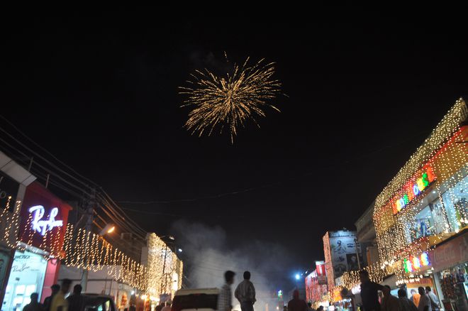 In this photograph taken on October 27, 2016, Indian shoppers watch a fireworks display amidst decorative lights at a local marketplace on the eve of Diwali festival in Jammu.