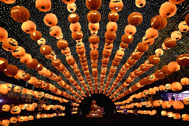This photo taken on October 24, 2016, shows a visitor posing for photos during a pumpkin lantern show in front of a shopping mall to mark the Halloween in Shenyang, northeast China’s Liaoning province.