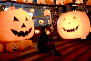 This photo taken on October 24, 2016, shows a visitor posing for photos during a pumpkin lantern show in front of a shopping mall to mark the Halloween in Shenyang, northeast China’s Liaoning province.