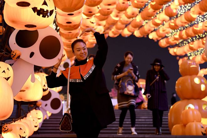 This photo taken on October 24, 2016, shows a visitor posing for photos during a pumpkin lantern show in front of a shopping mall to mark the Halloween in Shenyang, northeast China’s Liaoning province.