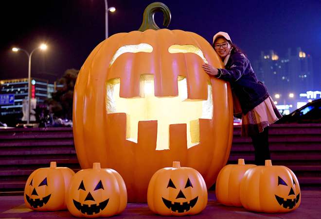 This photo taken on October 24, 2016, shows a visitor posing for photos during a pumpkin lantern show in front of a shopping mall to mark the Halloween in Shenyang, northeast China’s Liaoning province.