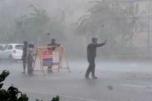 Traffic policemen direct vehicle during heavy rain caused by Cyclone Vardah in Chennai on December 12, 2016