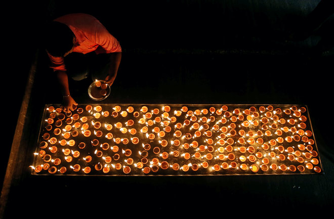 A Tamil devotee lights oil lamps at a religious ceremony during the Diwali festival at Ponnambalavaneshwaram Hindu temple in Colombo, Sri Lanka.
