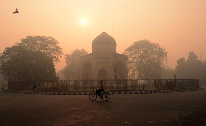 A cyclist rides along a street as smog envelops a monument in New Delhi on October 31, the day after the Diwali festival.