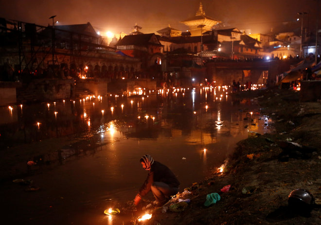 A devotee (C) performs religious ritual on the bank of Bagmati River flowing through the premises of Pashupatinath Temple, during the Bala Chaturdashi festival, in Kathmandu, Nepal, on November 28, 2016.